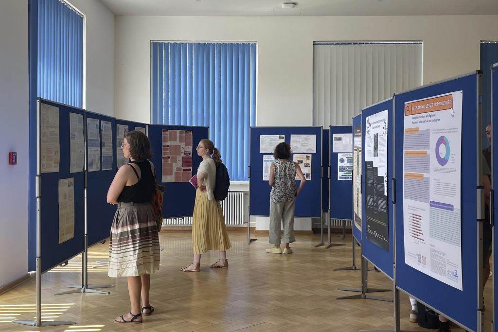 Foto: Stellwände mit wissenschaftlichen Postern und drei Betrachtende